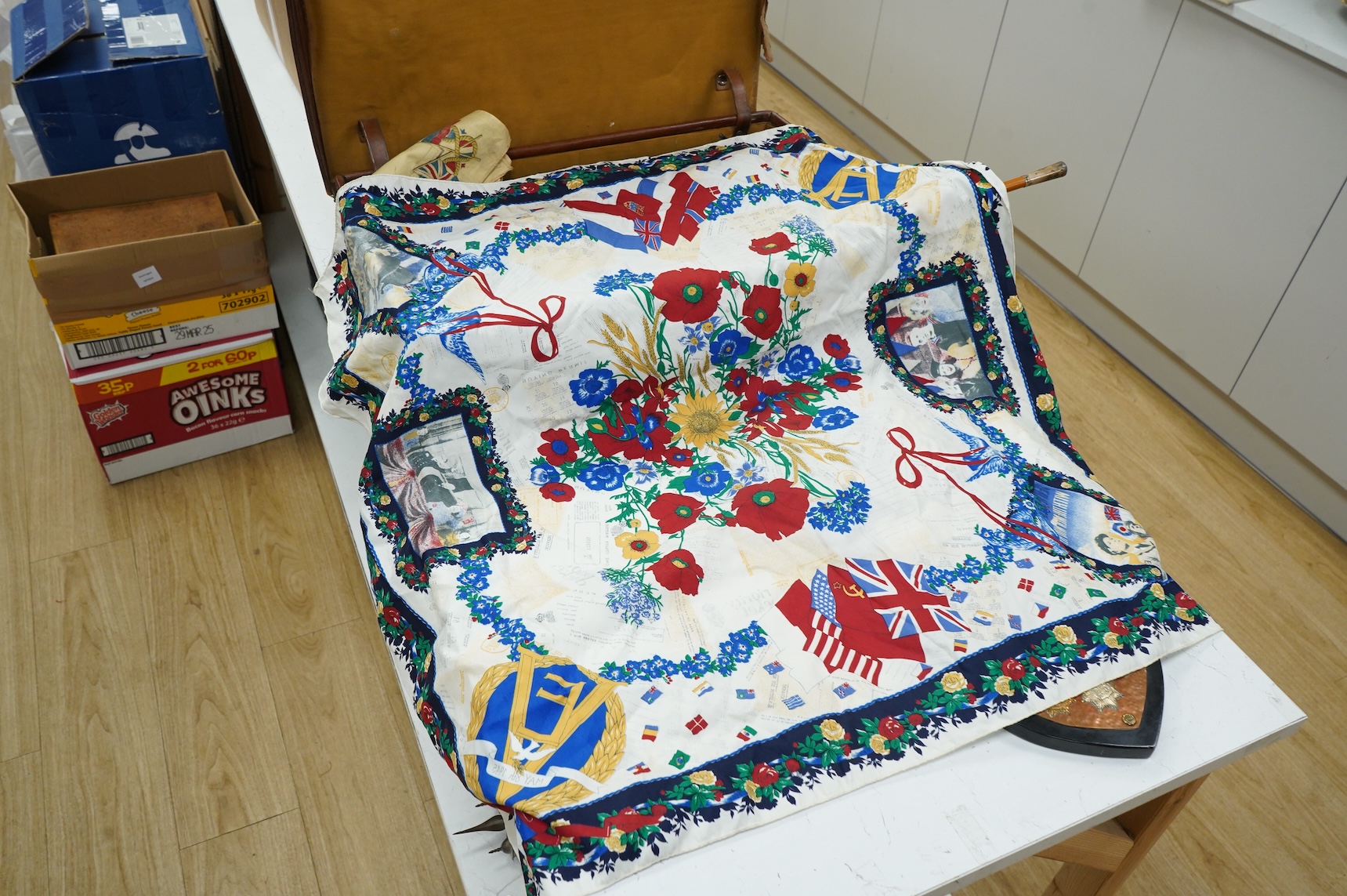 A suitcase of military related items, including; a Manchester Guardian issued early 20th century map of Europe printed on cotton, a First World War trench art match holder the base formed from a cartridge case, two swagg